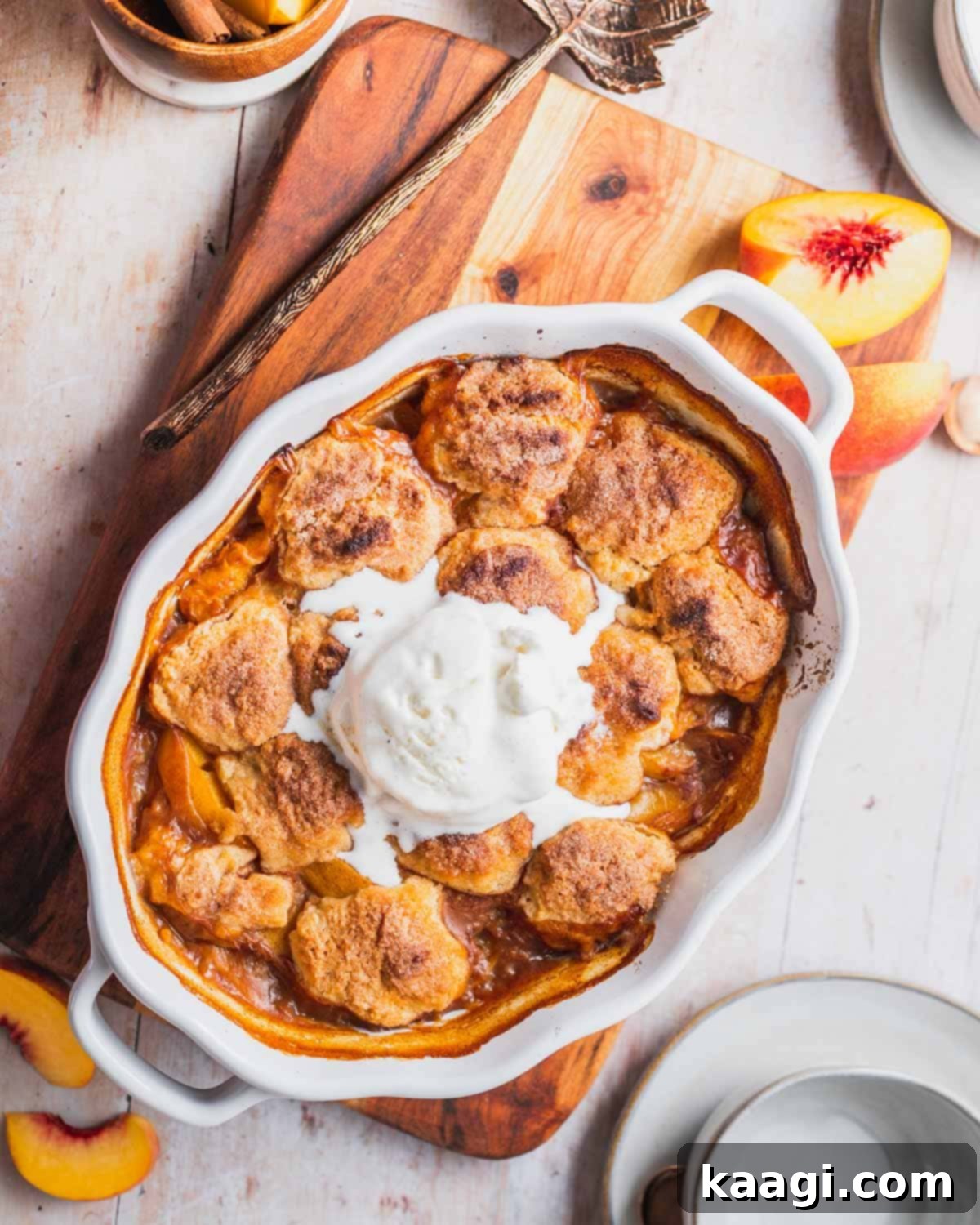 A serving of Easy Southern Bourbon Peach Cobbler, topped with a scoop of melting vanilla ice cream, showcasing its warm, fruity goodness.