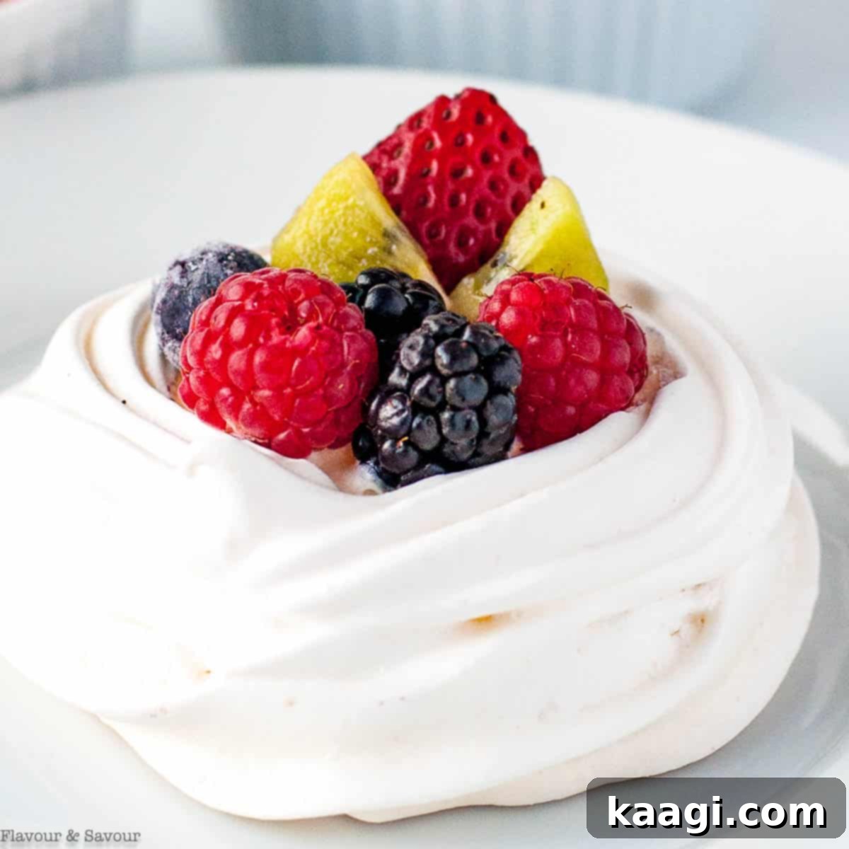 Individual Mini Pavlova with Berries, topped with fresh raspberries, blueberries, and a mint leaf.