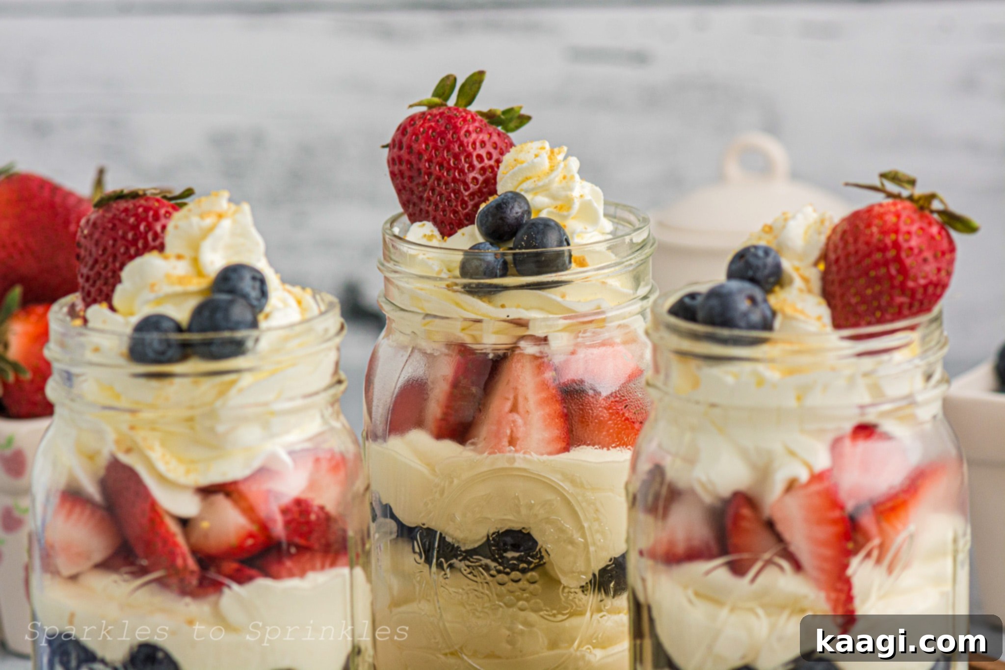 Red White and Blue No-Bake Cheesecake In A Jar, showing distinct layers of cheesecake, berries, and crumbs.