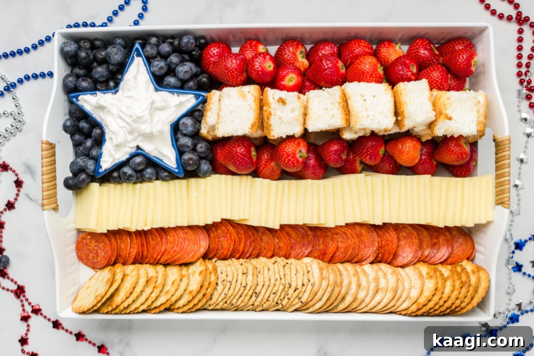 A beautifully arranged Patriotic Charcuterie Board filled with a variety of cheeses, fruits, and desserts in red, white, and blue.