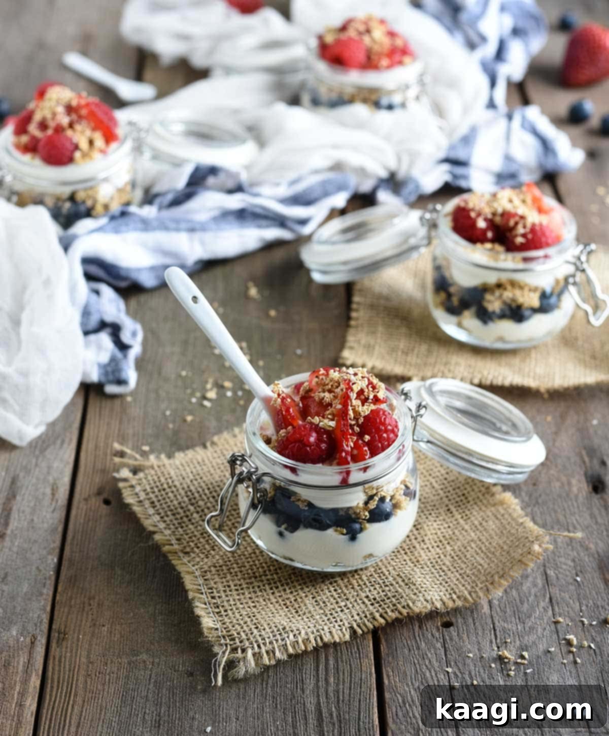Healthy Cheesecake Parfaits, layered in a glass with light cheesecake filling, oat crumbs, and fresh juicy berries.