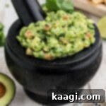 Close up shot of a mortar and pestle guacamole, showcasing its fresh and chunky texture.