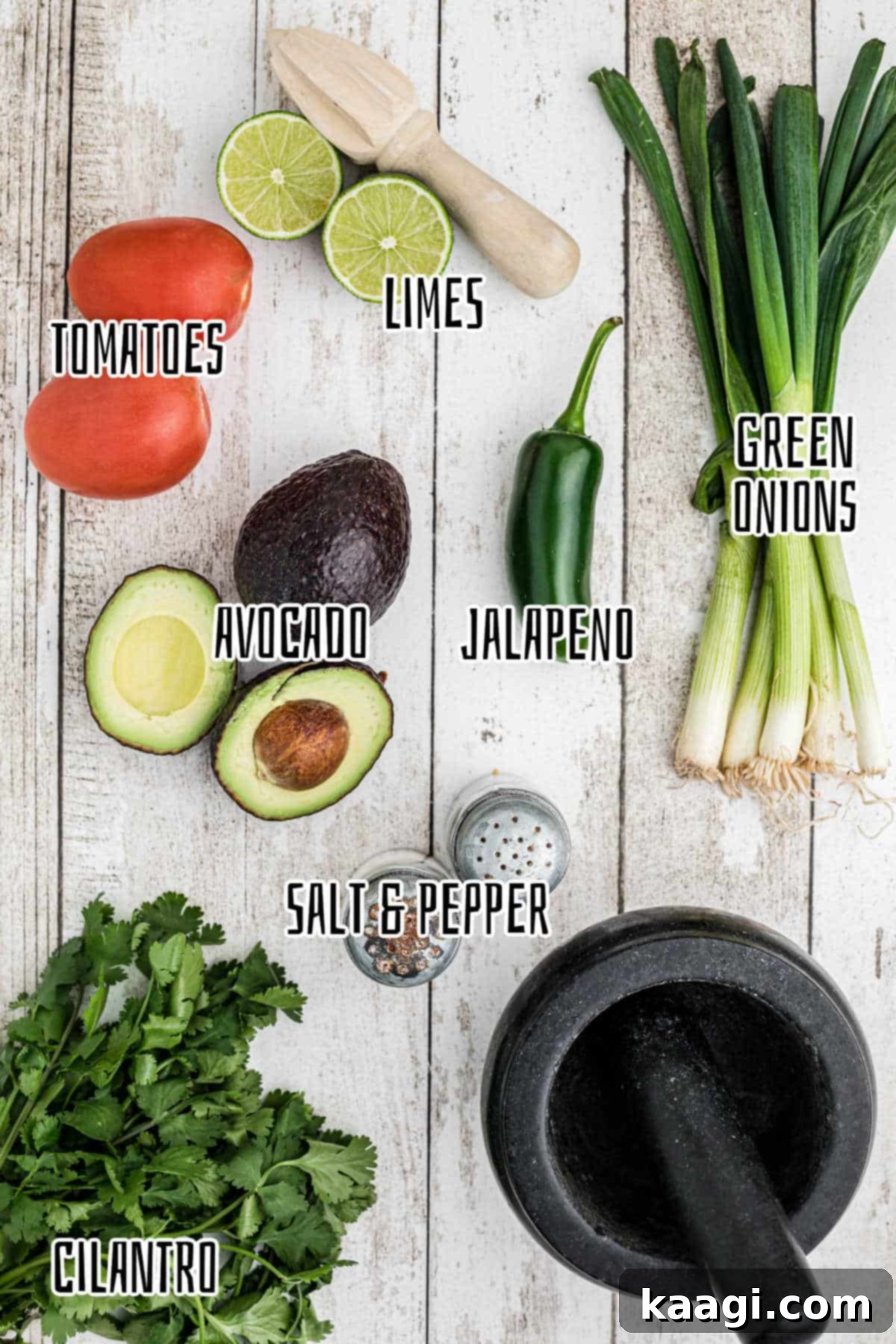A vibrant flat lay of fresh guacamole ingredients including ripe avocados, red tomatoes, green onions, cilantro, and a jalapeno.