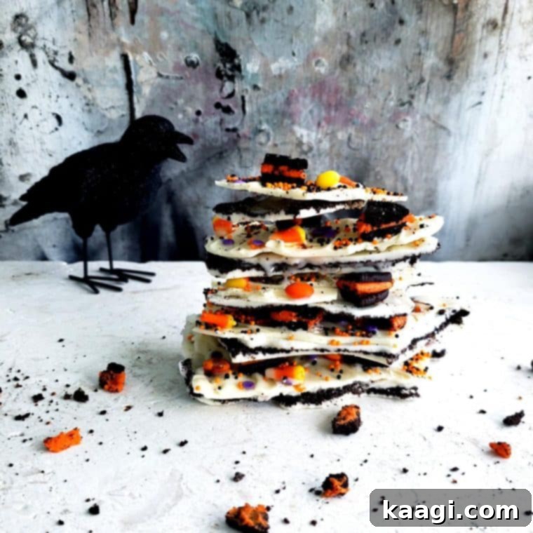 Halloween bark stacked in a pile, featuring white chocolate, Oreos, M&M's, and candy corn.
