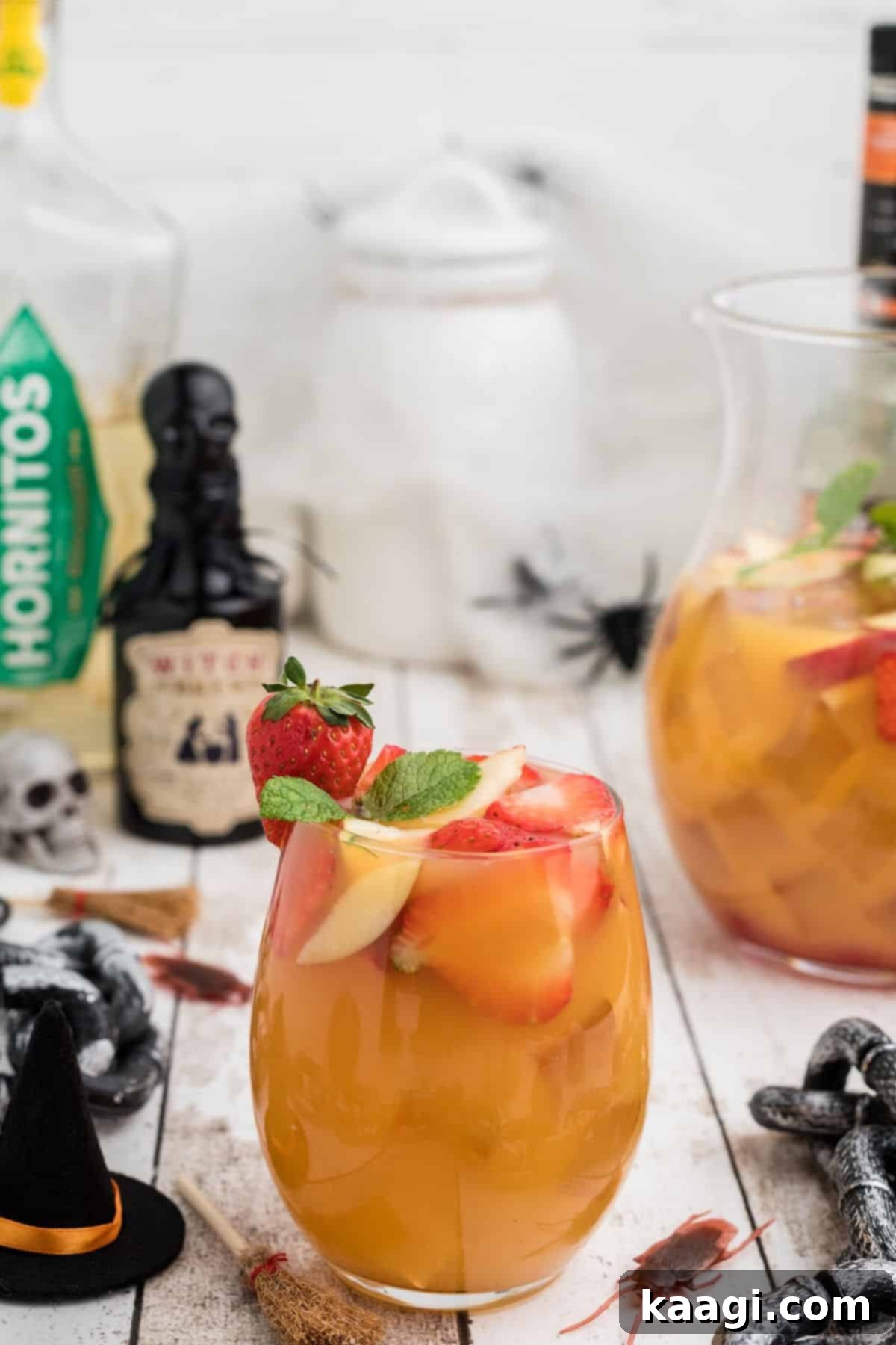 Glass of Halloween Jungle Juice in front with Halloween decorations all over the table.