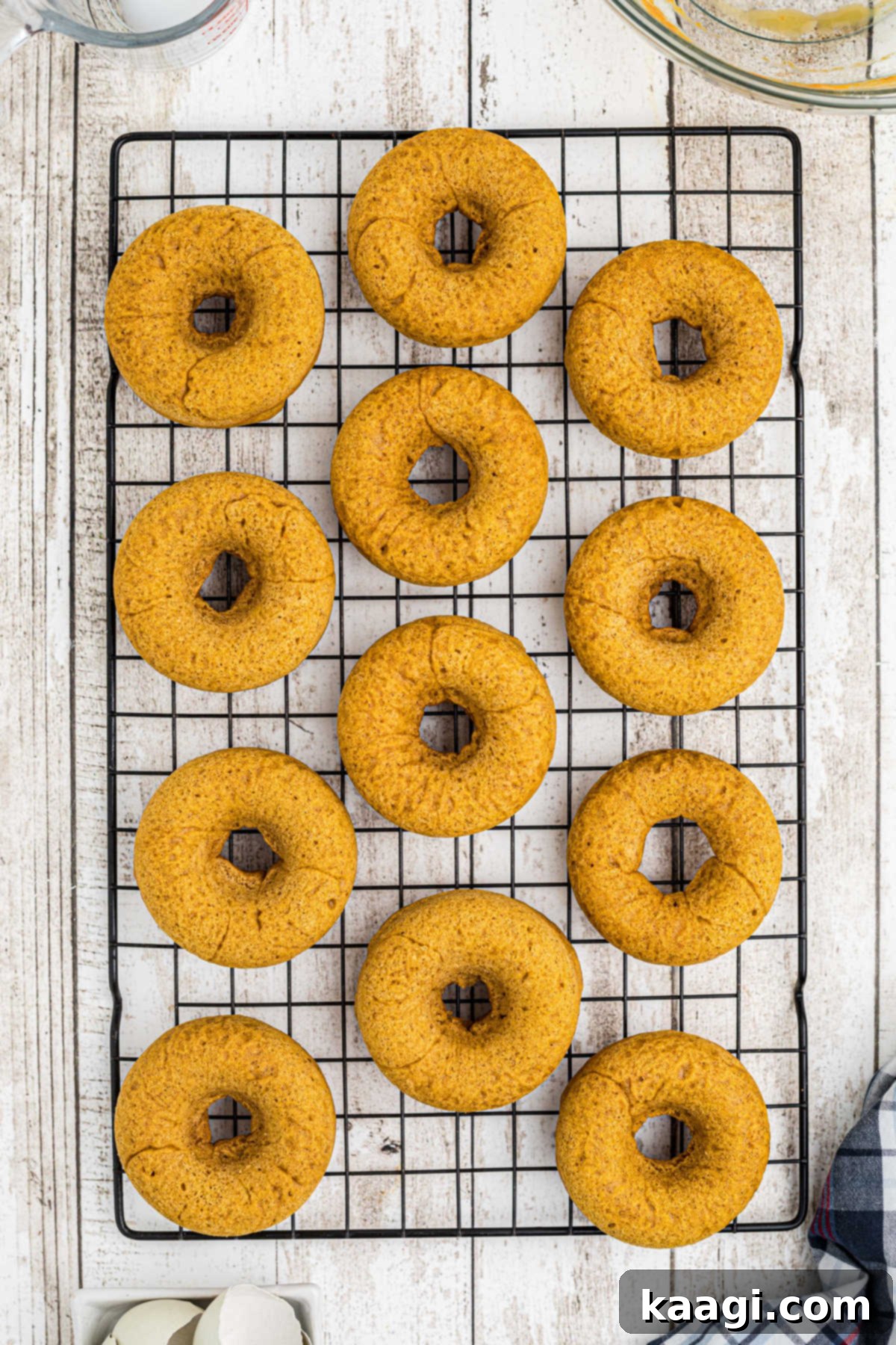 Freshly baked pumpkin spice donuts cooling on a wire rack, ready for frosting.