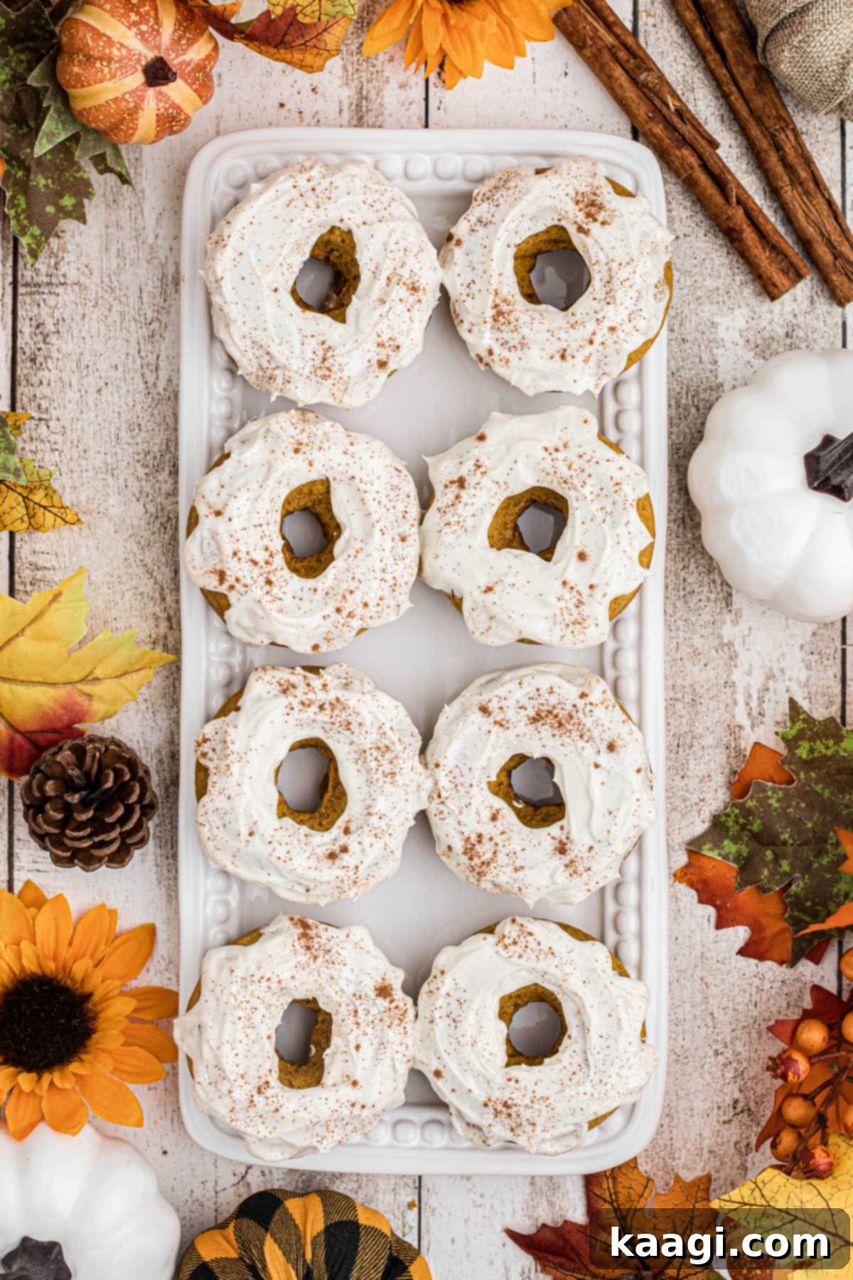 An overhead shot of a rustic wooden plate generously filled with perfectly baked and frosted pumpkin spice donuts, ready for sharing.