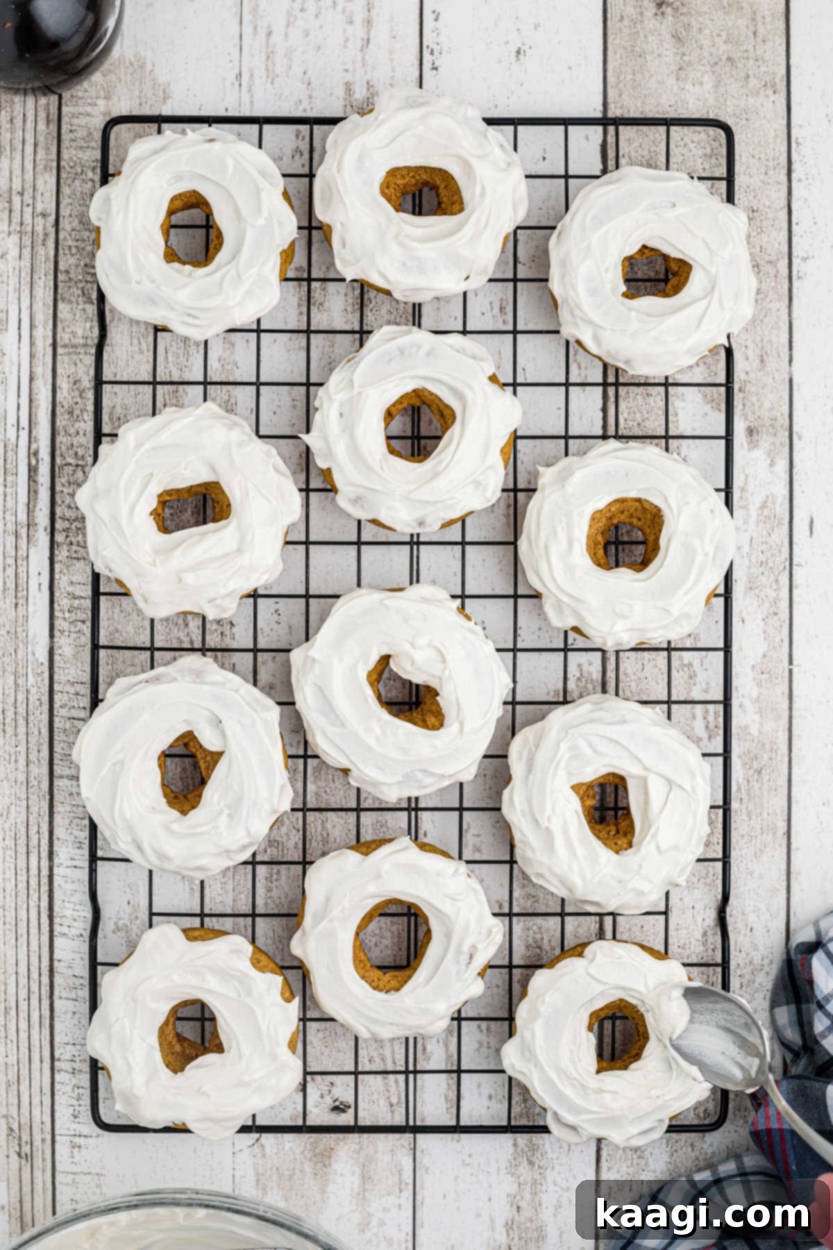 Overhead view of frosting being added to donuts.