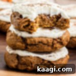 A stack of pumpkin cookies with cream cheese frosting, showcasing their deliciousness.