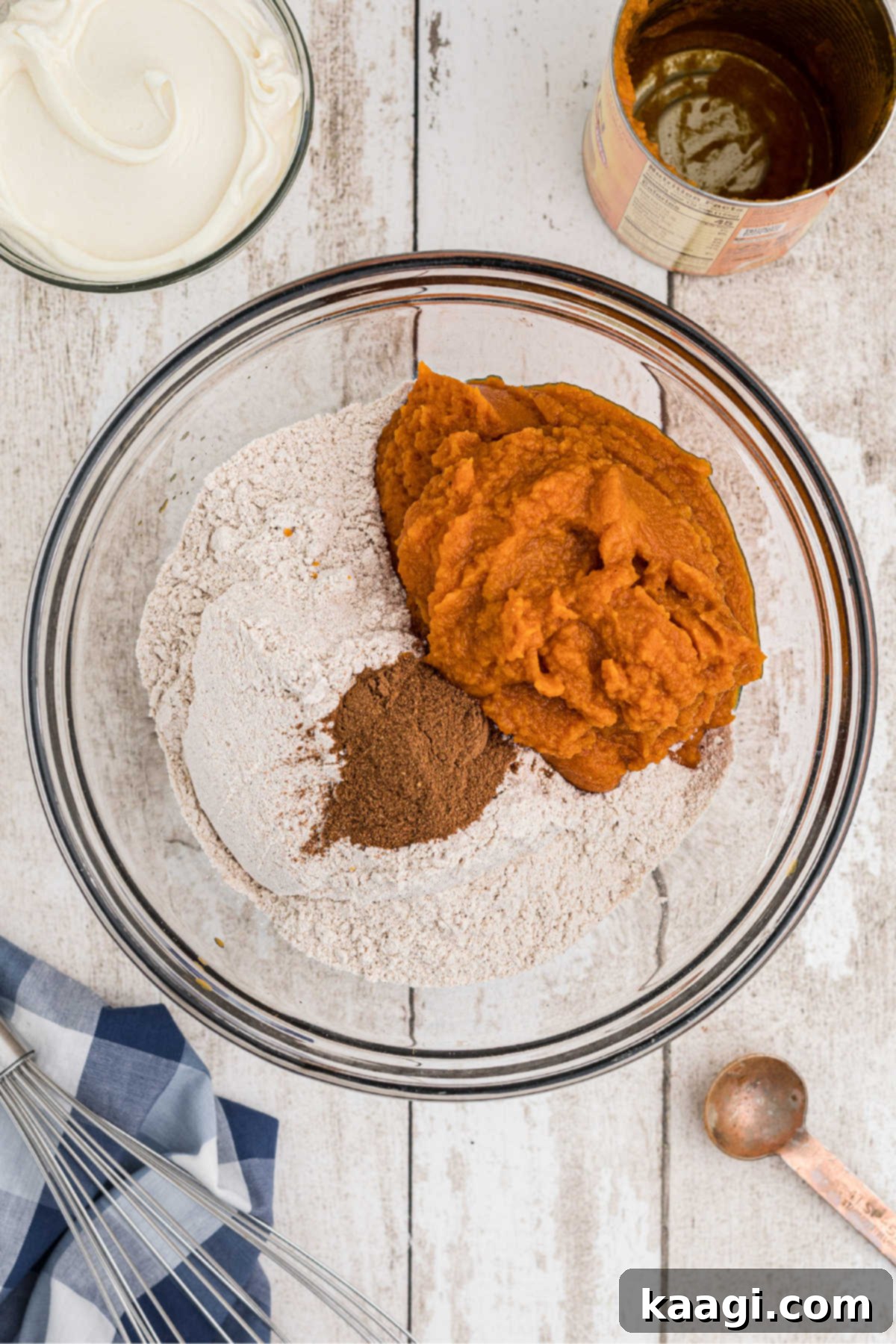A large mixing bowl containing spice cake mix, pumpkin puree, and pumpkin pie spice, ready to be combined.
