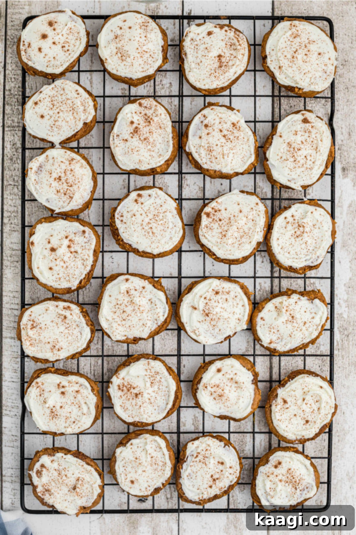 Freshly baked pumpkin spice cookies cooling on a wire rack before frosting, with a few already frosted.