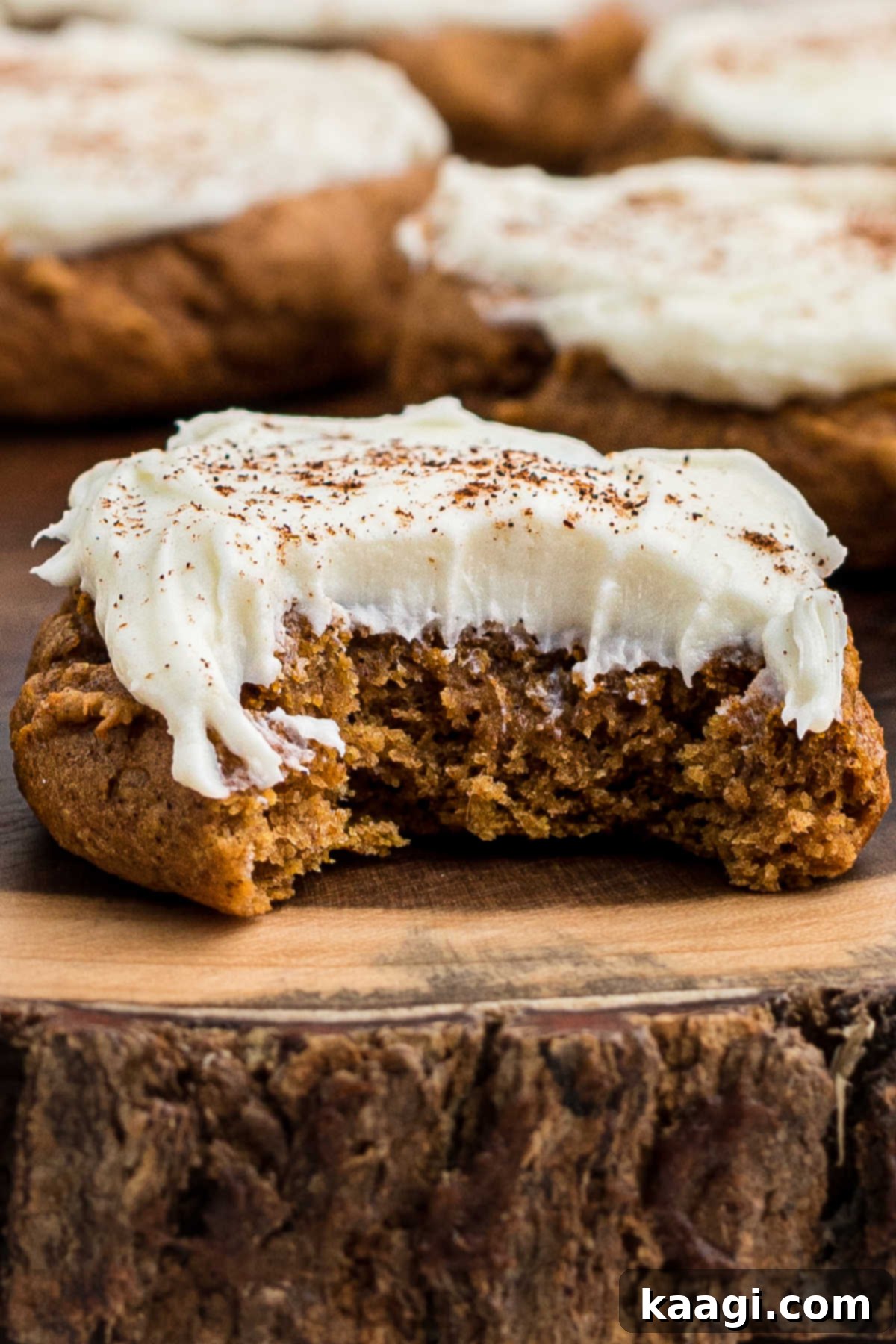 A delicious pumpkin spice cookie with a generous dollop of cream cheese frosting and a bite taken out.