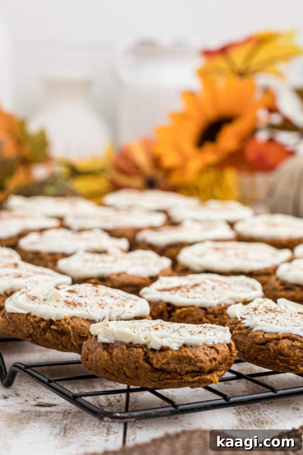 A beautifully arranged selection of Pumpkin Spice Cake Mix Cookies, frosted with cream cheese frosting, resting on a wire rack.