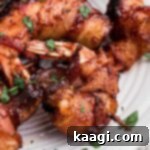 Smoked bacon wrapped shrimp on a plate, held together with a toothpick.