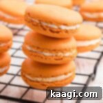 Harvest Pumpkin Macaron Bites 7 A close up shot of a stack of three pumpkin spice macarons, highlighting their delicate texture, 'feet', and creamy filling.