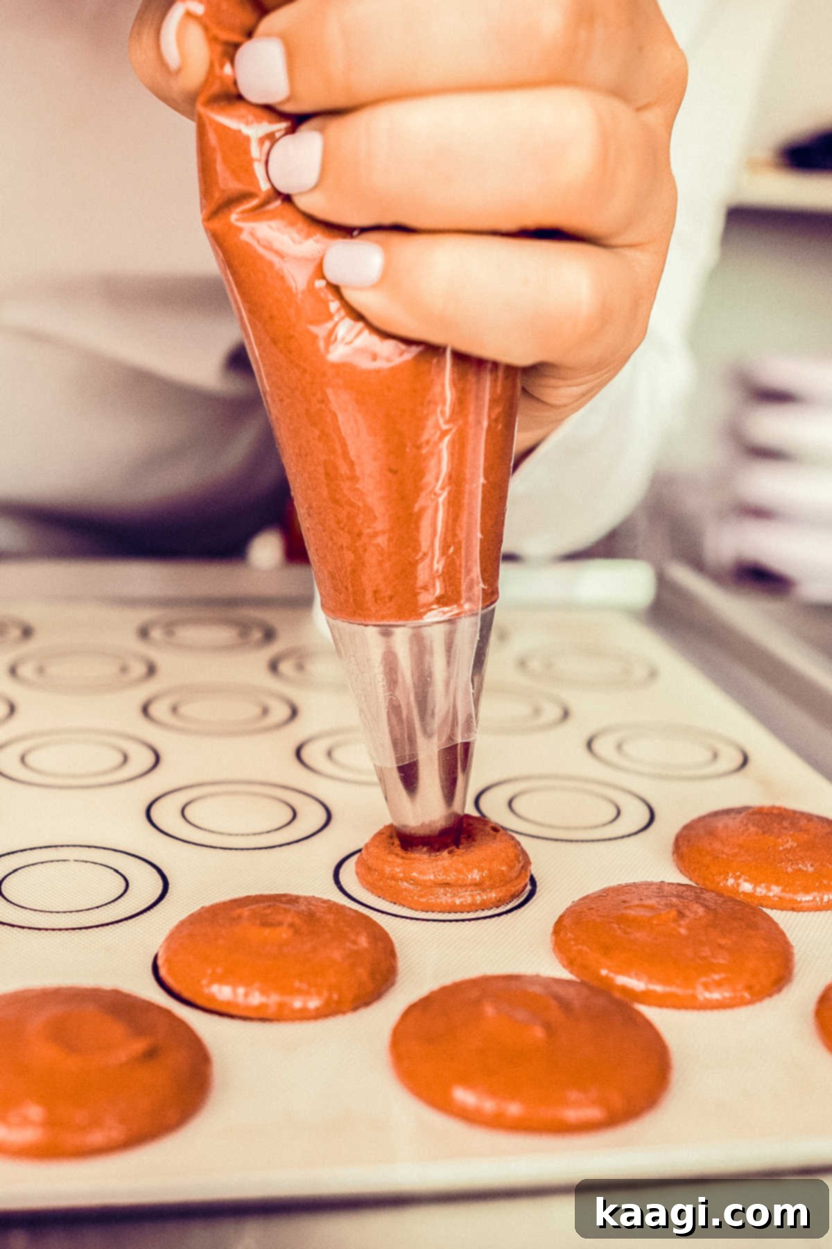 Harvest Pumpkin Macaron Bites 4 A skilled hand expertly piping uniform pumpkin spice macaron dough circles onto a baking sheet, guided by circular stencils.