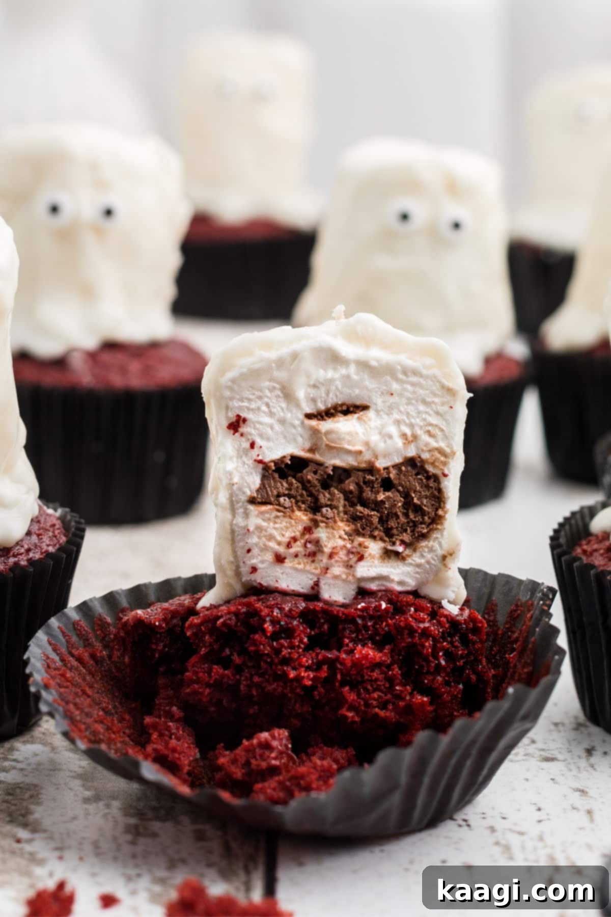 Fluffy Phantom Cupcakes 7 Close up of the inside of a ghost cupcake, revealing the red velvet cake and chocolate filling in the marshmallow.