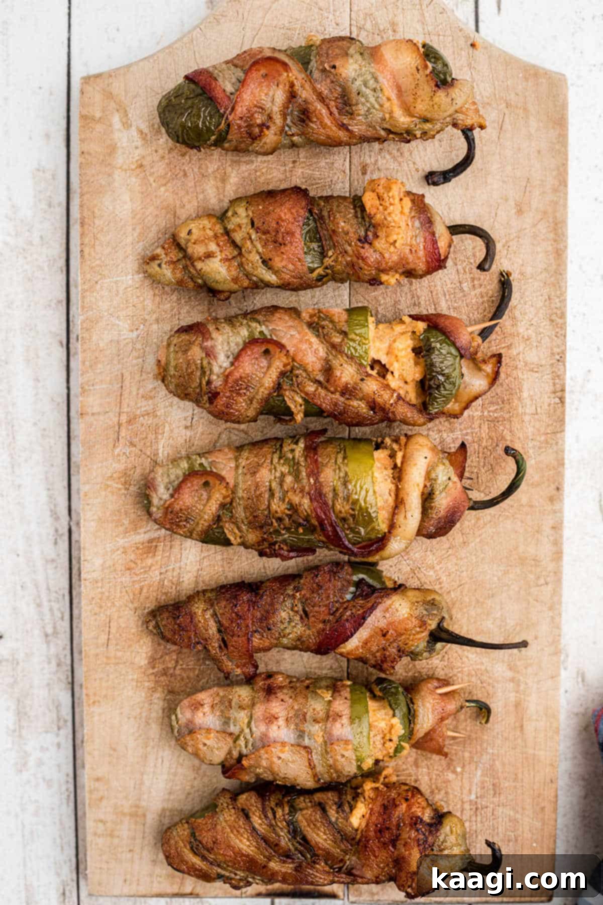 Fiery Smoked Jalapeno Bites 5 Beautifully arranged smoked jalapeno poppers on a rustic wooden board, ready to be enjoyed.