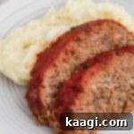 Close up shot of two delectable slices of venison meatloaf perfectly plated alongside a serving of creamy mashed potatoes, garnished and ready for a meal.