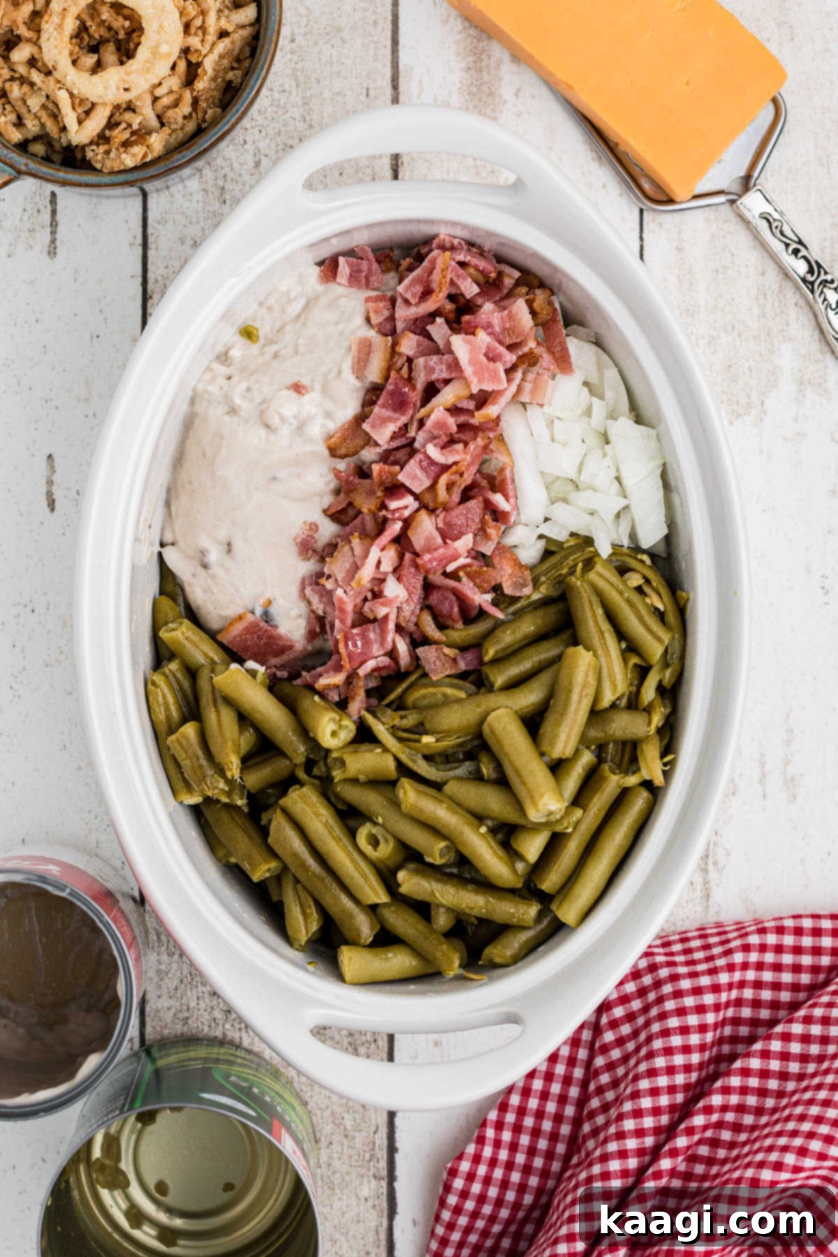 A small casserole dish filled with a mixture of green beans, cream of mushroom soup, cooked bacon, and diced onions, ready for the air fryer.