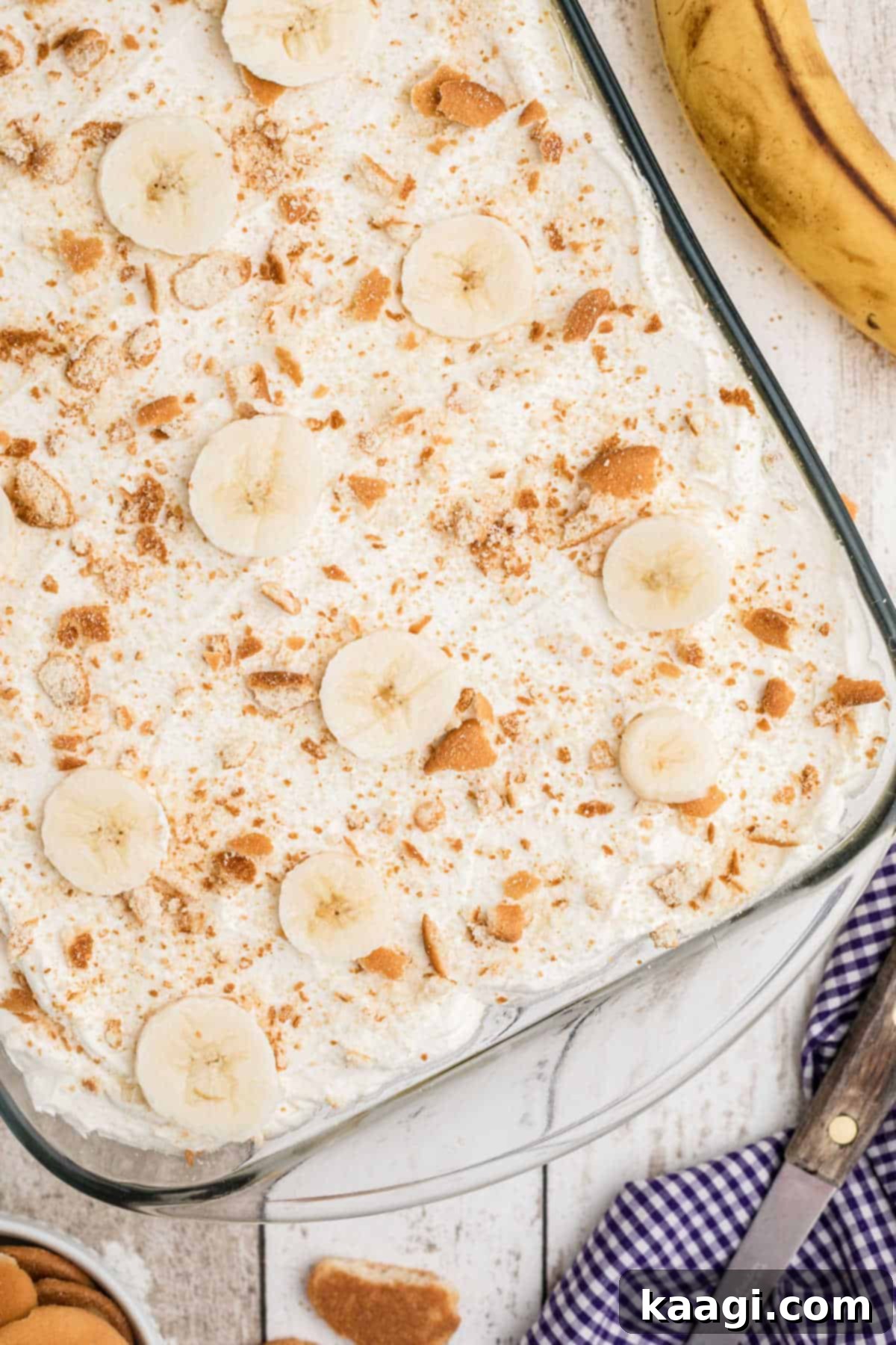An overhead view of southern banana pudding in a casserole dish, garnished with whipped cream and vanilla wafers.