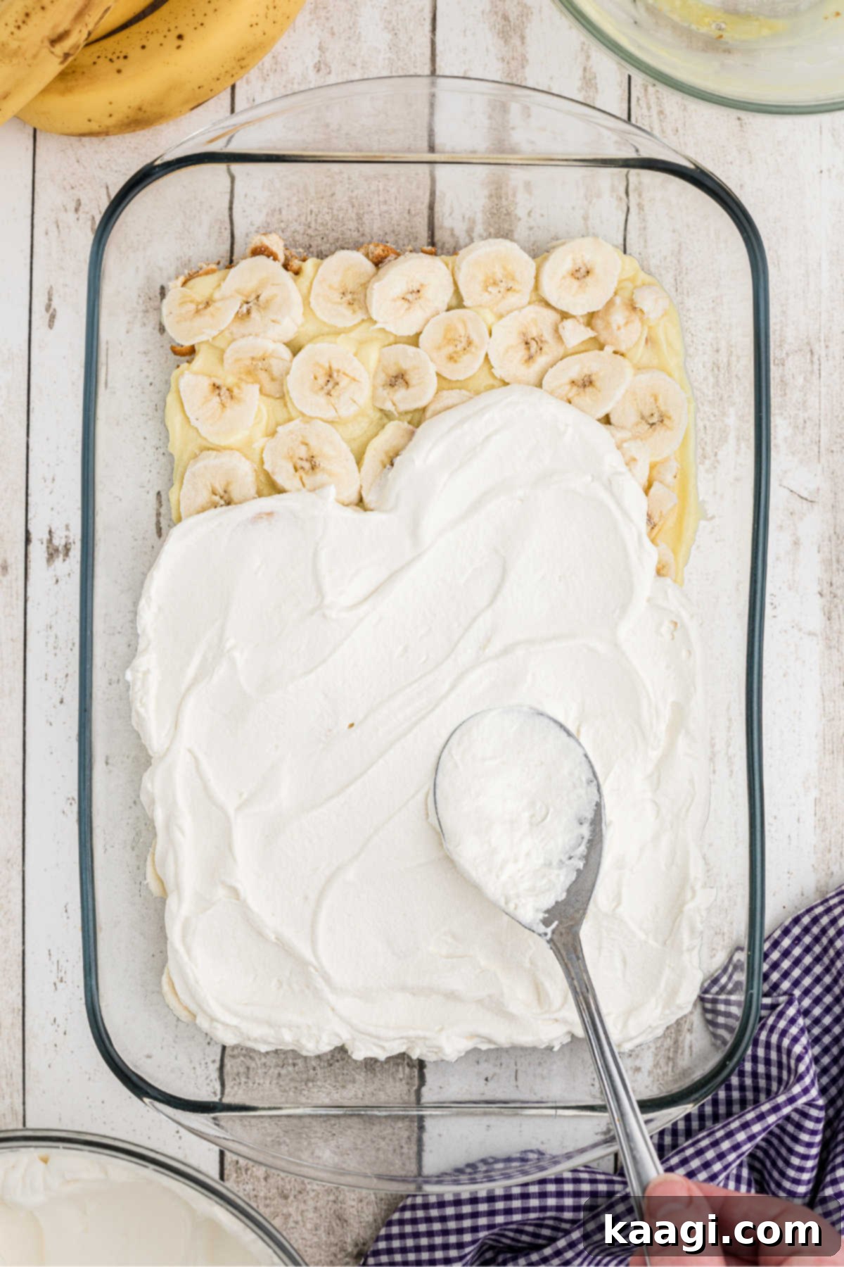 Cream being spread on top of a layer of sliced bananas.