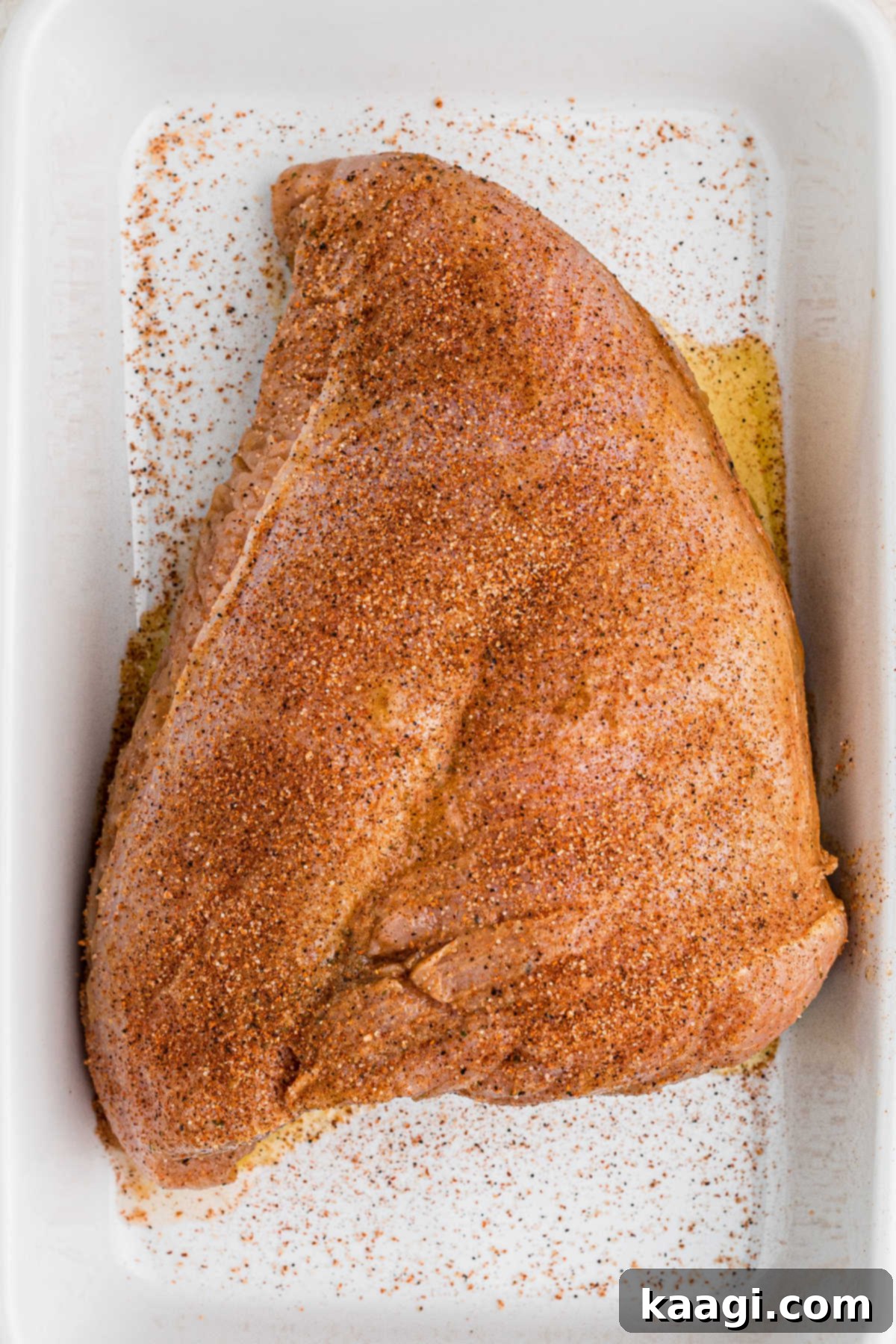 A turkey breast sitting in a dish full of seasoning.