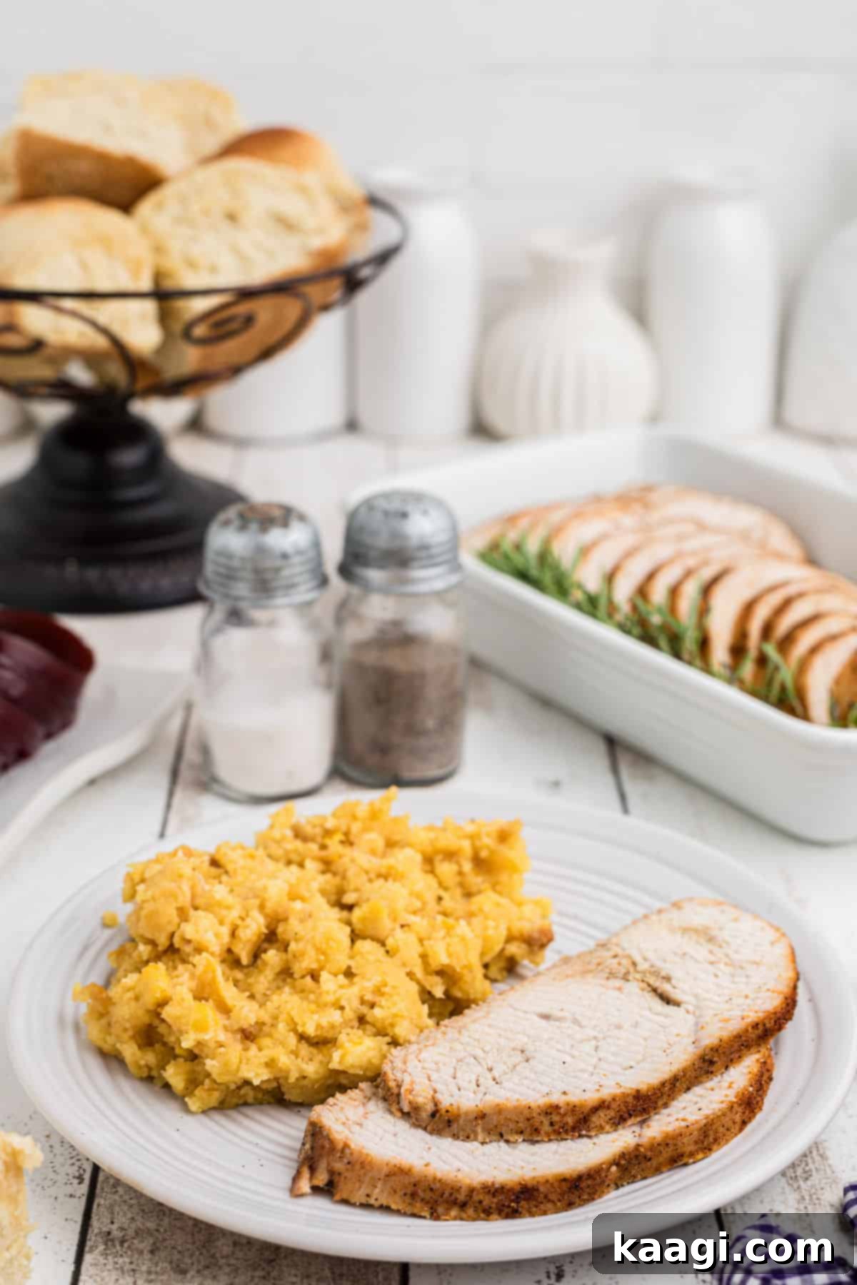 Sliced cajun turkey breast on a plate with some corn casserole.