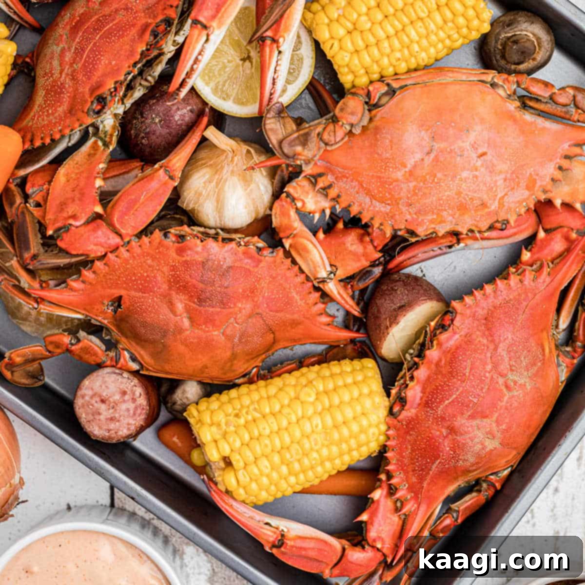 A tray of boiled crabs with veggies and dipping sauce.