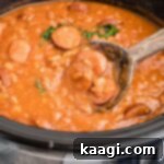 Smoky Kielbasa and Sweet Baked Beans Slow Cooker Delight 6 Close up of kielbasa and baked beans with a wooden spoon taking some.