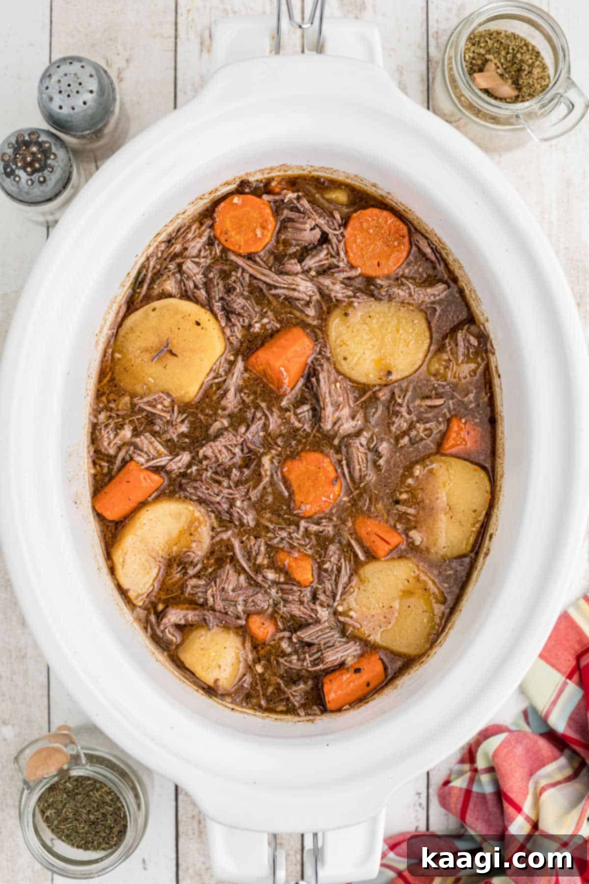 Tender Slow Cooker Tri Tip Roast 4 A white crock pot full of perfectly cooked tri tip roast with tender carrots and potatoes, ready to be served.