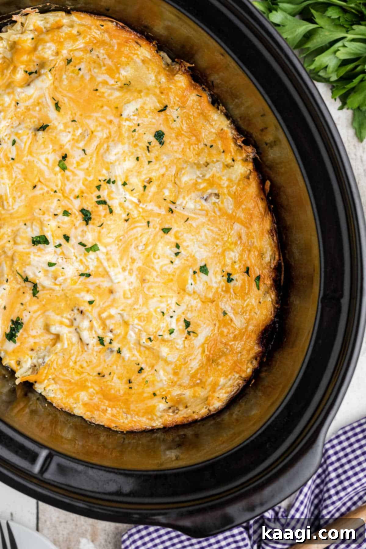 Overhead shot of a slow cooker with a hash brown casserole inside, looks cheesy.