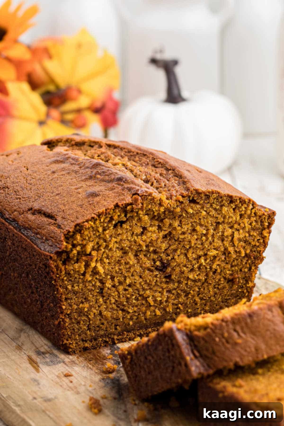 Close up side view of a sliced Amish Pumpkin Bread loaf, showing its moist, tender crumb and two perfect slices ready to be eaten.