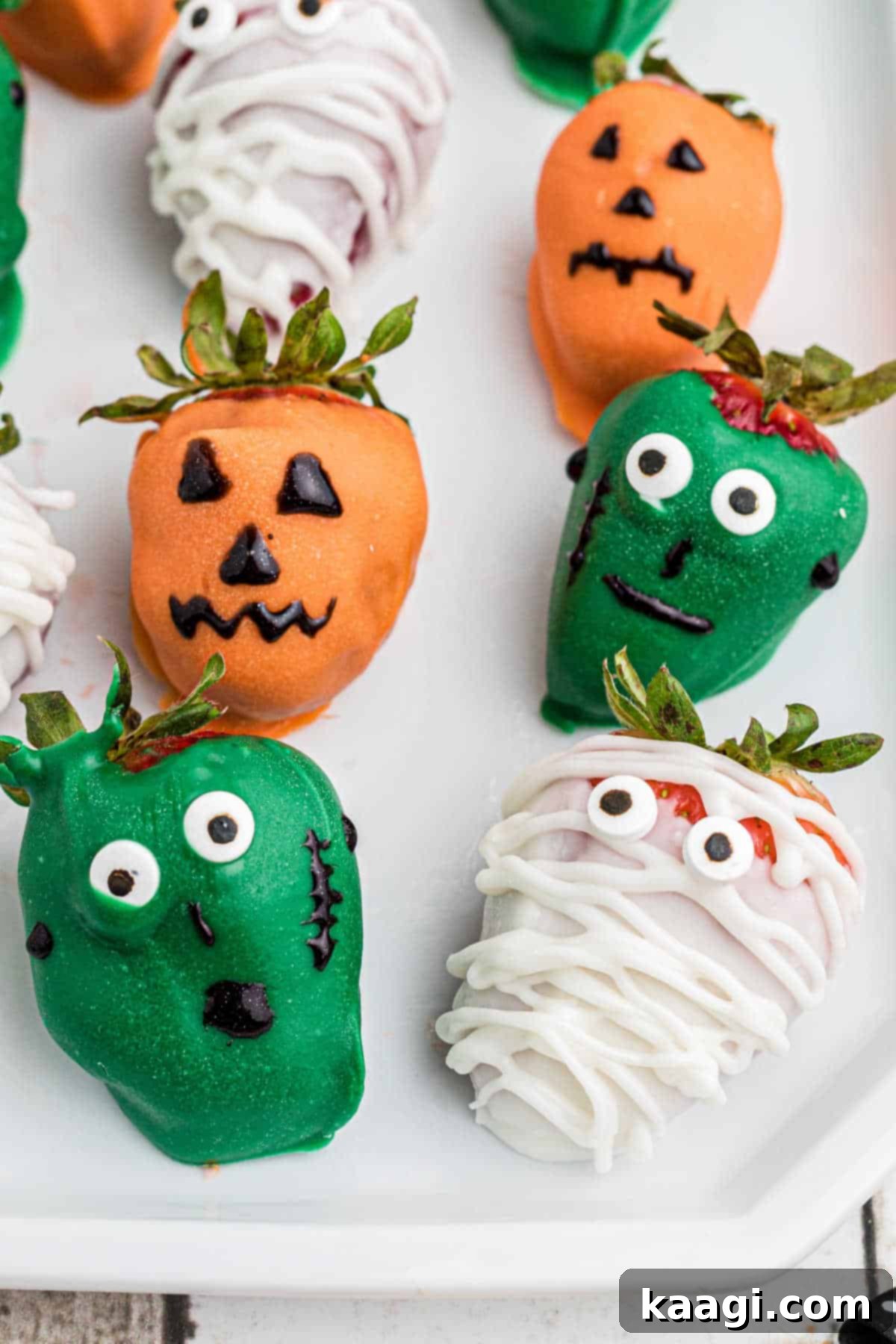 Close up of some Halloween chocolate strawberries, showcasing a mummy, Frankenstein, and a Jack-o'-lantern side-by-side.