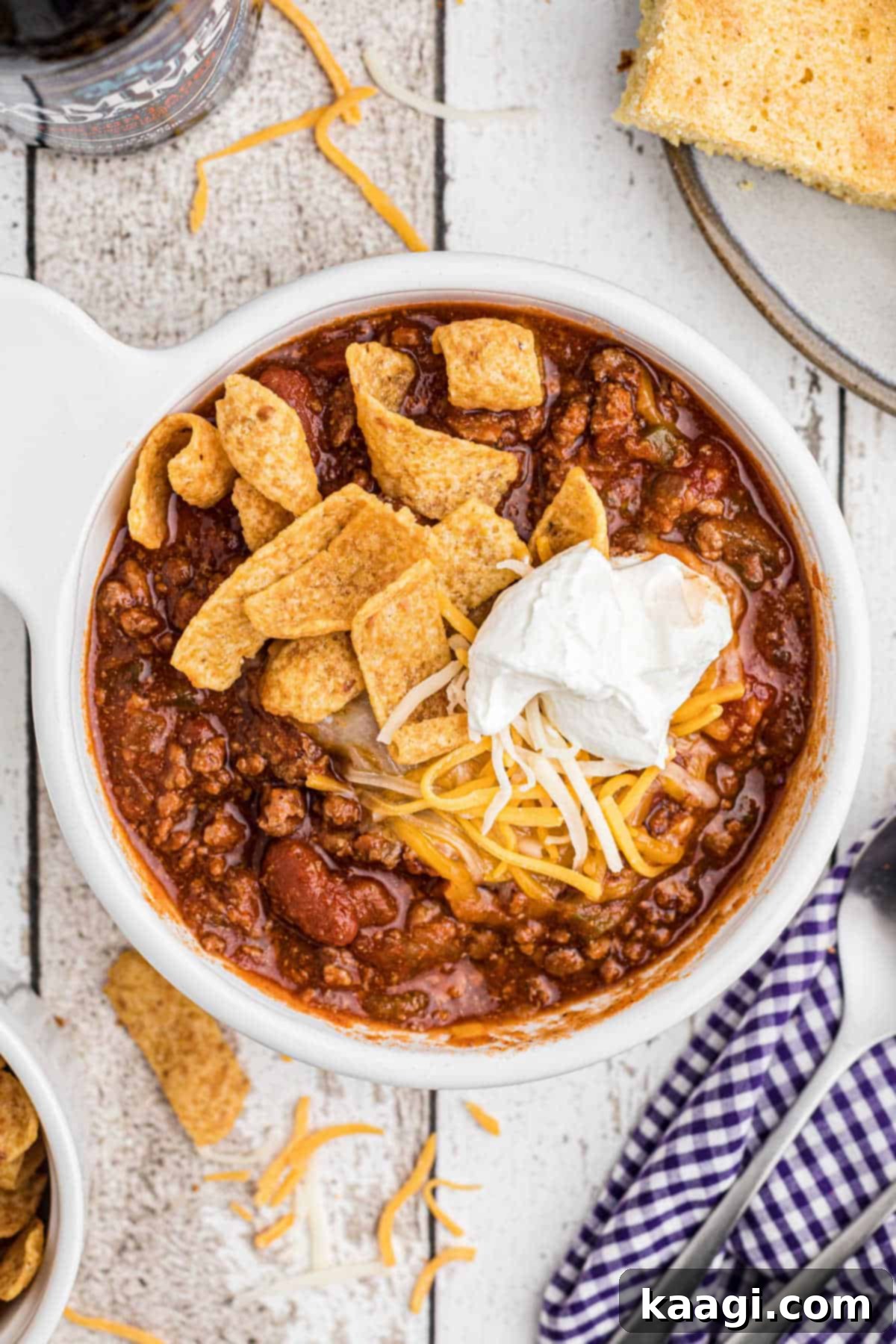 Overhead close up of a bowl of crock pot chili with fritos and sour cream, ready to eat.