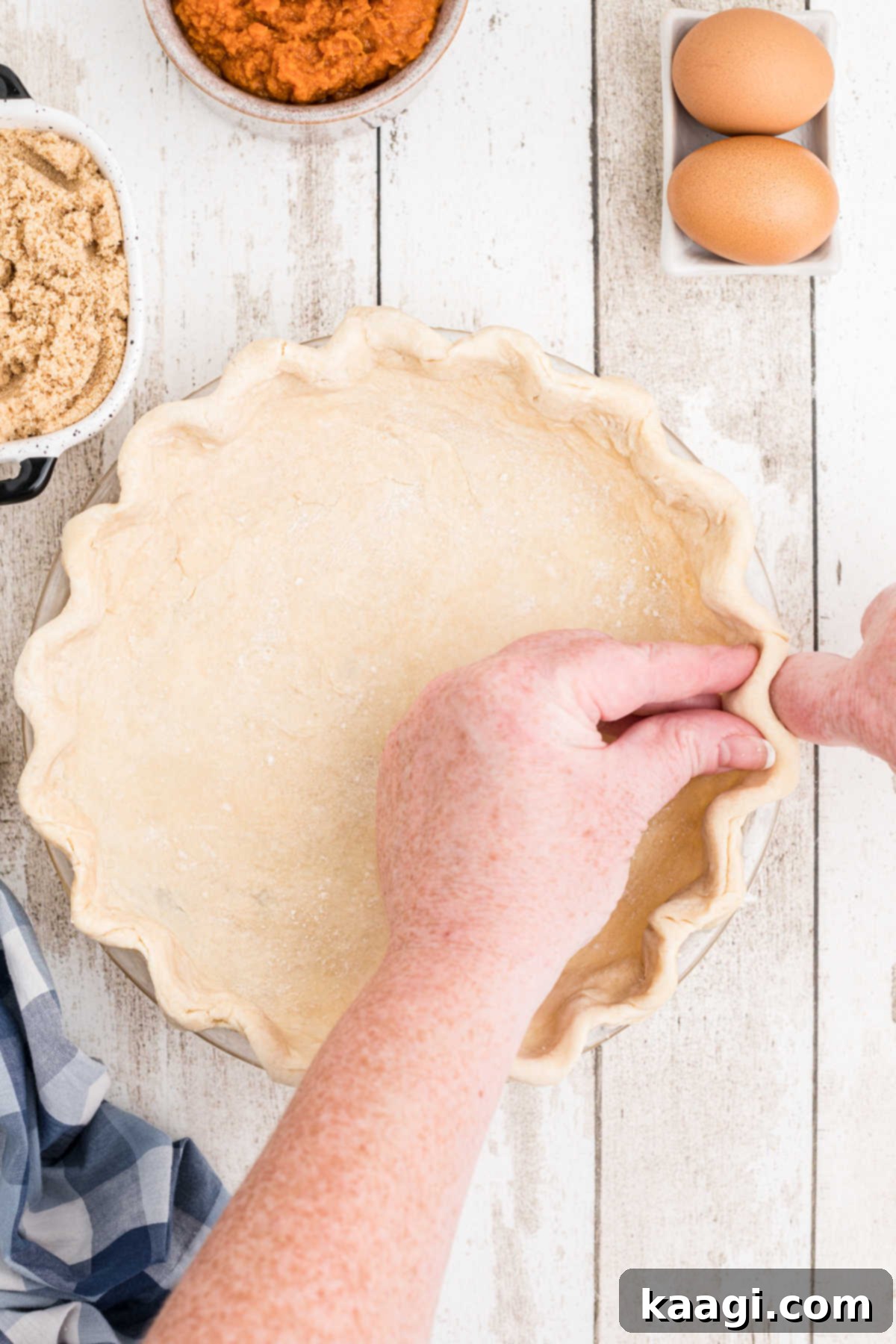 A pie crust being fluted ready to be baked.