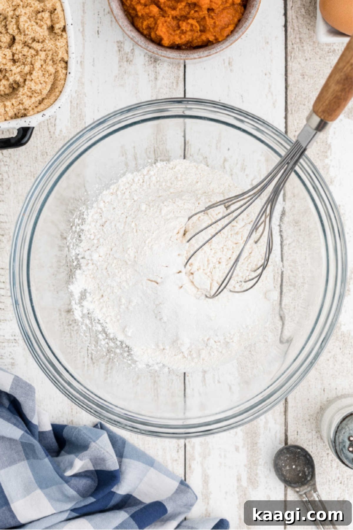 A large mixing bowl with flour and other ingredients and a whisk.