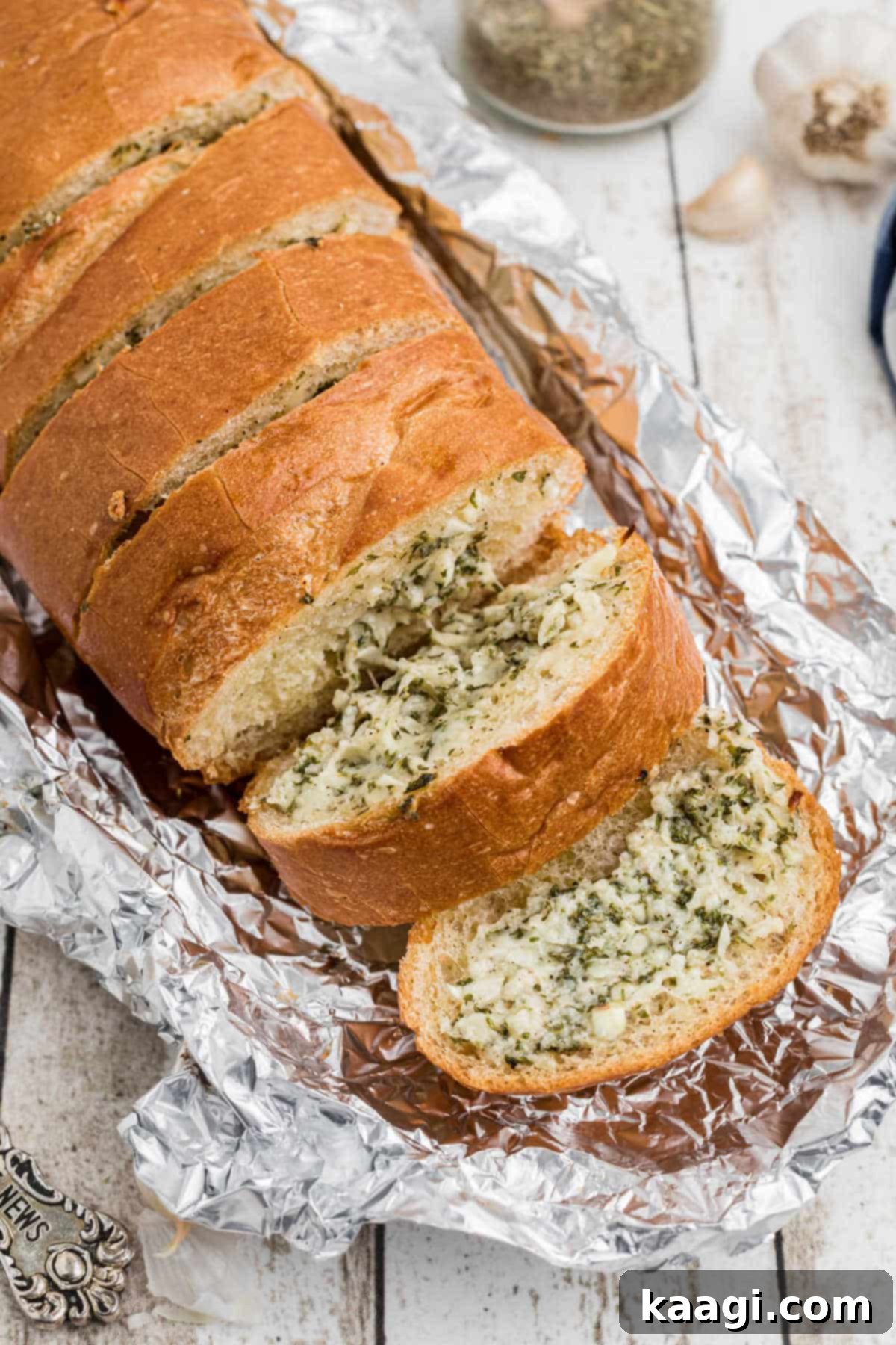 Overhead shot of a loaf of stuffed garlic bread slightly opened between slices, showcasing the melted cheese and herbs within.
