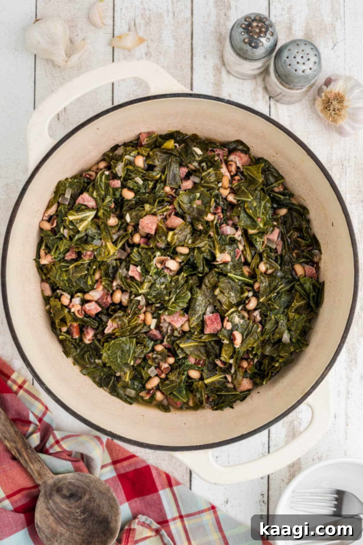 Overhead shot of a Dutch Oven full of steaming black eyed peas and collard greens, garnished for serving.