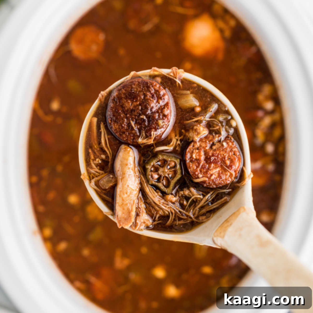 Overhead shot of a ladle coming out of a slow cooker with gumbo.