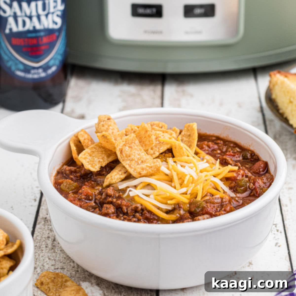 Close up side view of a bowl of beer chili with a crock pot in the background.