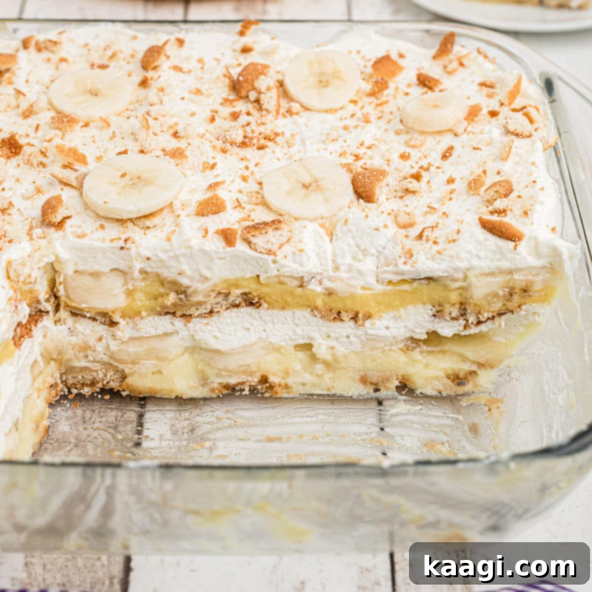A dish full of luscious no-bake banana pudding, with a few pieces already enjoyed, showcasing its creamy layers, soft vanilla wafers, and sliced fresh bananas.