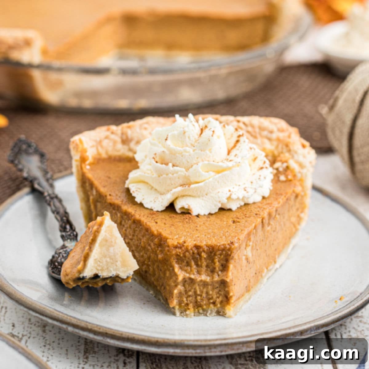 Close-up of a delectable Amish pumpkin pie, with a fork having just removed a piece, revealing the creamy, spiced texture, adorned with a dollop of fresh cream on top.
