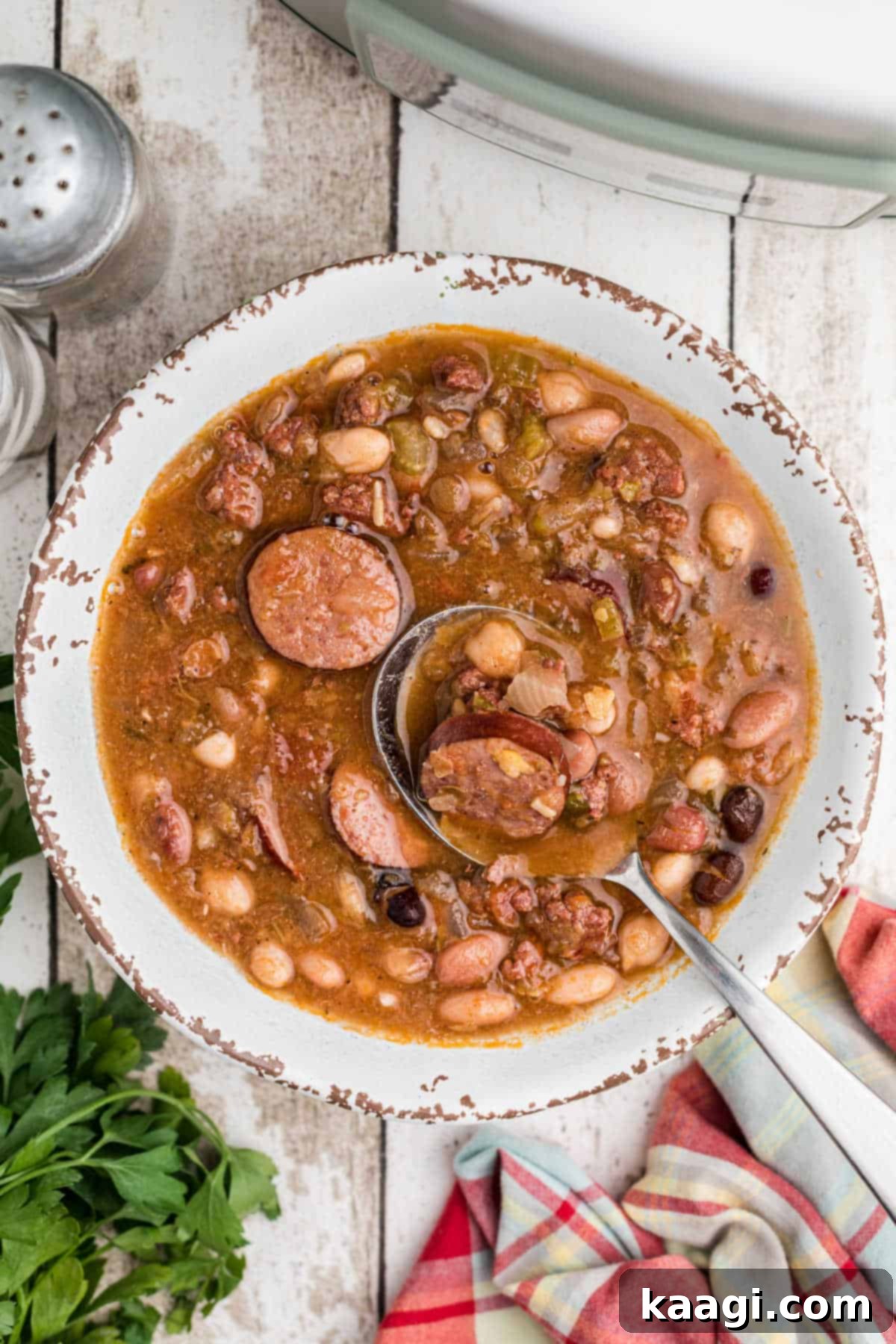 Overhead close up of a bowl of slow cooker Cajun 15 bean soup, garnished with fresh herbs.