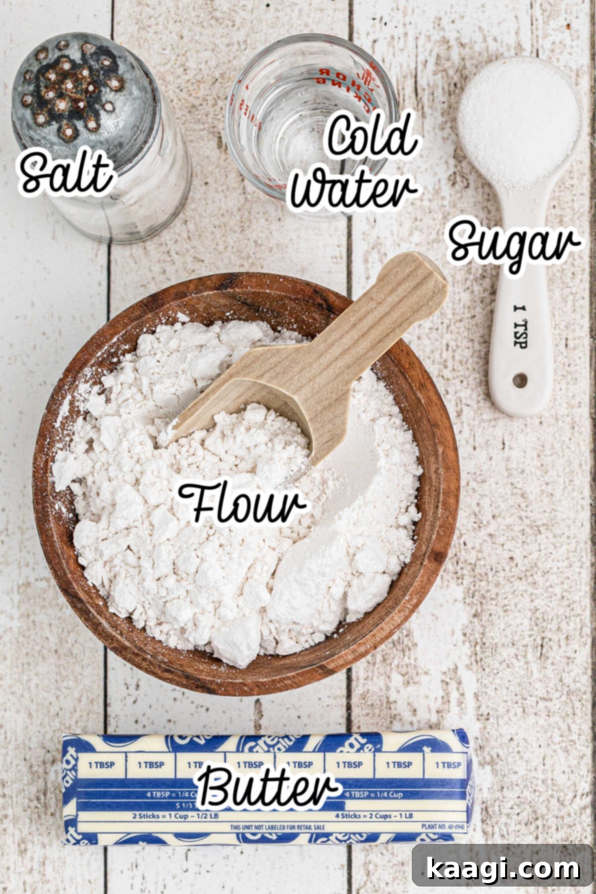 A flat lay of the simple ingredients needed for Amish Pie Crust, including butter, flour, sugar, salt, and a glass of cold water.