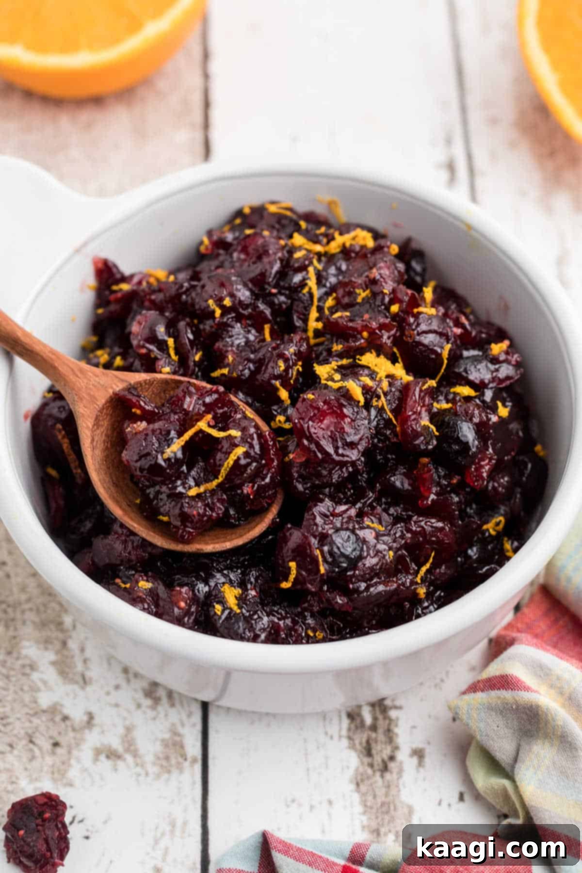 A close up of a bowl of dried cranberry sauce with a spoon digging in.