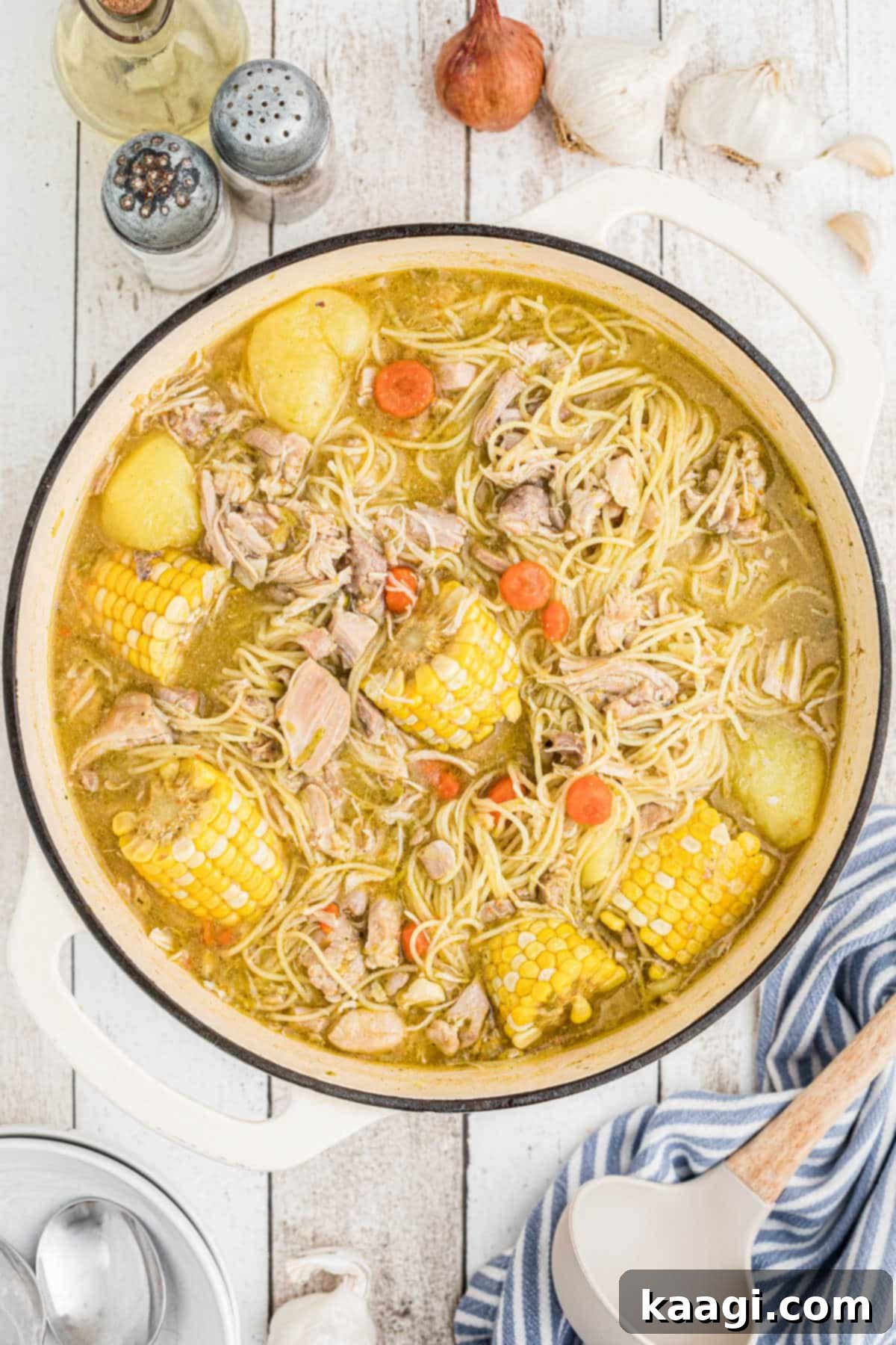 An overhead shot of a pot full of Cuban chicken soup, brimming with rich broth, tender chicken, and colorful vegetables.