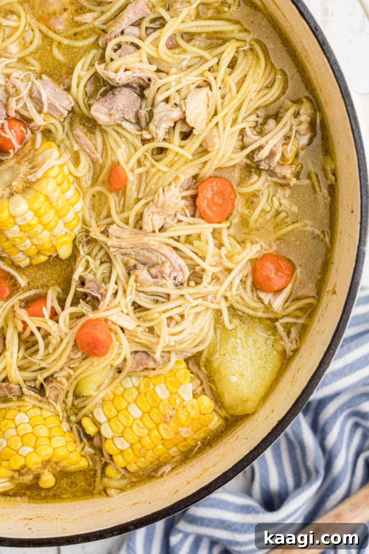 An overhead close up shot of the side of a pot full of Cuban chicken soup, showing its rich texture and steaming warmth.