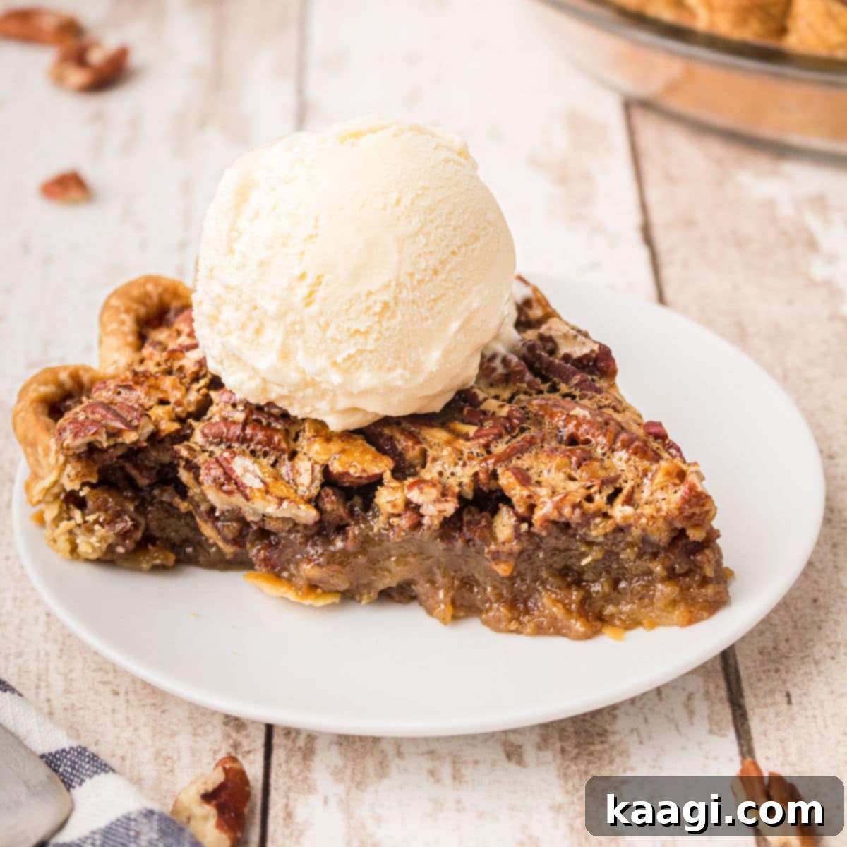 A plate with a slice of pecan pie, adorned with a scoop of vanilla ice cream melting on top.