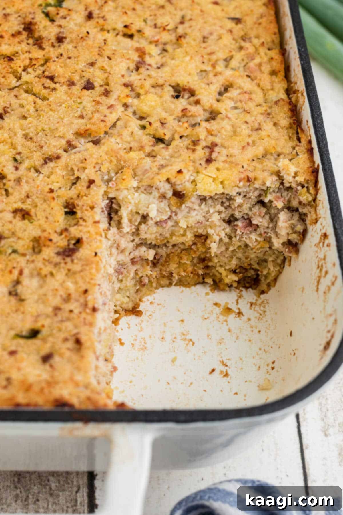 Cajun Cornbread Comfort 4 View of the side of a dish with a cornbread dressing in it, with the corner missing.